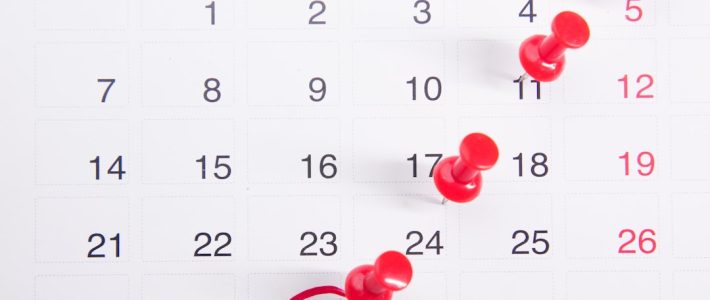 Practical Everyday Routines for Managing Anxiety and Emotional Wellbeing A calendar page with red push pins marking specific dates, illustrating the concept of predictability through scheduling